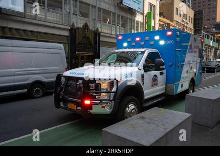 New York, USA - 20 juillet 2023 : une ambulance traversant la circulation dans une rue de Manhattan, New York, avec ses lumières et sirène allumées.. Banque D'Images