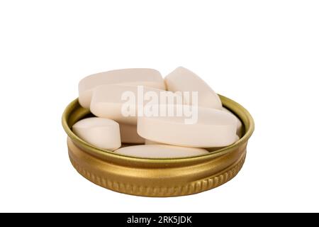 Plusieurs pilules médicales dans un bouchon métallique d'une bouteille en verre, macro, isolé sur un fond blanc. Banque D'Images