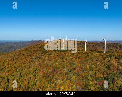 Une vue aérienne d'un moulin à vent sur une montagne couverte de forêts en automne par une journée ensoleillée Banque D'Images