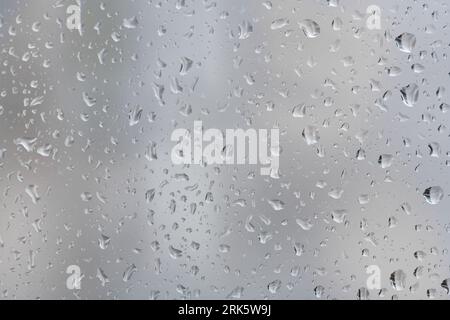 Plan rapproché de gouttelettes de pluie se formant sur la vitre Banque D'Images
