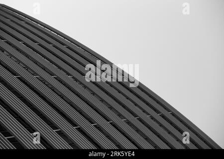 A grayscale shot of a modern building roof against the backdrop of a sky. Stock Photo