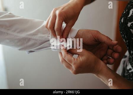 Deux personnes dans un studio, une femme ajustant une robe tandis qu'une autre personne met une chemise blanche Banque D'Images