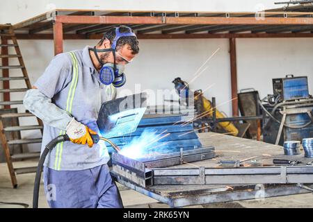 homme de travail dans un atelier/usine. homme travaillant sur le métal. travail des métaux. soudage du fer et utilisation d'équipements industriels Banque D'Images