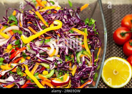 Un bol en céramique blanche rempli d'une variété d'ingrédients sains et colorés de salade, y compris des tomates, des concombres et des légumes verts feuillus, garni de fre Banque D'Images
