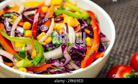 Gros plan d'un bol de salade de légumes fraîchement préparée, comprenant un mélange coloré d'ingrédients, y compris des tomates, des poivrons, des oignons et des légumes verts Banque D'Images