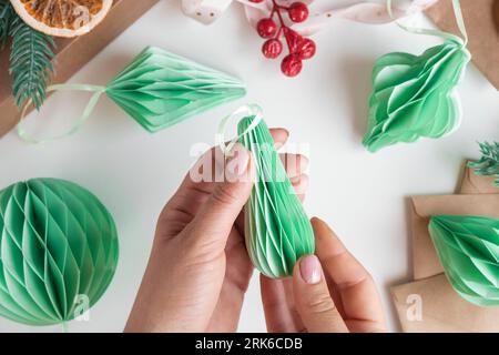 Les mains féminines déplient des ornements en nid d'abeille de Noël en papier. Décoration sans plastique pliable faite à la main. Concept d'artisanat de créativité hivernale. Mode éco DIY. SC Banque D'Images