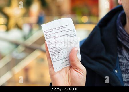 reçu papier d'épicerie dans les mains masculines gros plan. Traduction du russe : Batyr Mall, poulet kebab, boisson. café, plats à emporter. Pavlodar, Kaza Banque D'Images