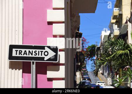Un panneau de rue animé se dresse devant un bâtiment majestueux, entouré d'arbres luxuriants et verdoyants Banque D'Images