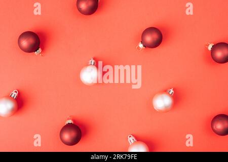 Boules de Noël blanc et rouge foncé sur fond rouge, texture. Banque D'Images