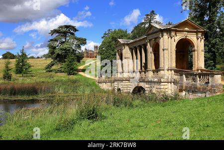 Stowe Landscape Gardens dans le Buckinghamshire du Nord, Angleterre avec le pont palladien au premier plan et le temple gothique sur la colline Banque D'Images