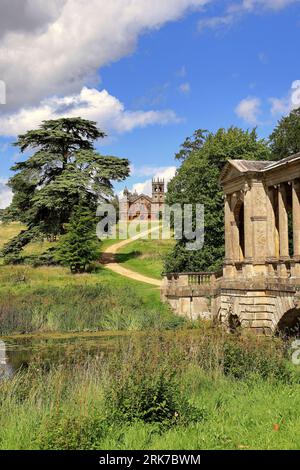 Stowe Landscape Gardens dans le Buckinghamshire du Nord, Angleterre avec le pont palladien au premier plan et le temple gothique sur la colline Banque D'Images