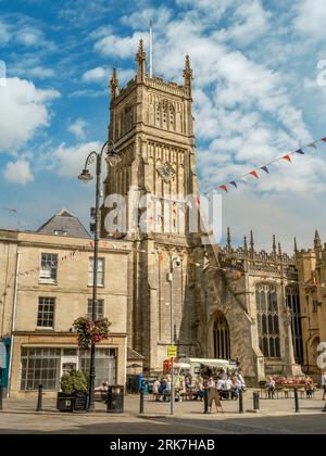 Cirencester, Gloucestershire - England. People sit and enjoy a snack in the late summer sunshine under the impressive tower of Cirencester Parish Chur Stock Photo