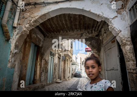 Une fille vue regardant autour de la médina de la ville portuaire tunisienne Sfax, qui est devenue un point chaud de migration vers l'Europe. La Tunisie est devenue le premier pays de départ pour les personnes qui tentent de rejoindre l’Europe en traversant la mer Méditerranée sur la route migratoire dite de la Méditerranée centrale, que l’ONU a qualifiée de la plus meurtrière au monde. Banque D'Images