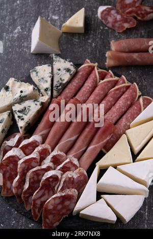 photo saucisse et tranches de fromage, assortiment, apéritif, sur un fond sombre Banque D'Images