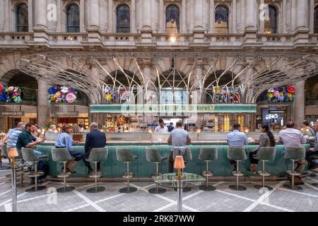 Un groupe diversifié d'amis et de famille assis ensemble dans un bar, profitant d'une gamme de cocktails colorés au Fortnum et Mason dans le Royal Exchange Banque D'Images