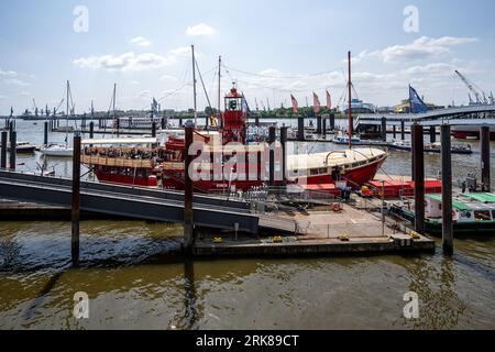 A vibrant red boat is docked at a marina, surrounded by a variety of other boats including sailboats Stock Photo