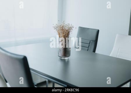 A glass vase containing a colorful bouquet of flowers displayed atop a wooden table Stock Photo