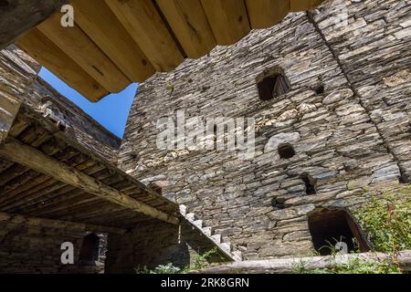 Une vue d'en bas de la passerelle en bois et de la façade de la tour revêtue d'ardoise dans le village fortifié de Shatili, Khevsureti, Géorgie. De petites ouvertures dans le mur de la tour servaient de failles ; les passerelles en bois reliant les tours permettaient la défense sur plusieurs niveaux simultanément. 3e rue, Shatili, municipalité de Dusheti, Mtskheta-Mtianeti, 1800, Géorgie Banque D'Images