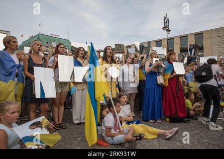 Les Ukrainiens se sont réunis à la porte de Brandebourg à Berlin le 24 août 2023 pour marquer le jour de l'indépendance de l'Ukraine. Mais ce n'était pas une célébration ordinaire. La foule, une mer de tournesols, de drapeaux, de bannières et de vêtements ukrainiens traditionnels, est venue avec un message de souvenir et de résilience. Dans un geste symbolique, les participants ont brandi des miroirs, 503 au total, chacun reflétant le visage d'un enfant perdu dans la guerre de la Russie contre l'Ukraine. Scintillant sous le soleil couchant, les miroirs ont servi de rappel obsédant aux 503 enfants ukrainiens dont la vie a été abruptement et impitoyablement prise dans le conflit. «Ukrainien Banque D'Images