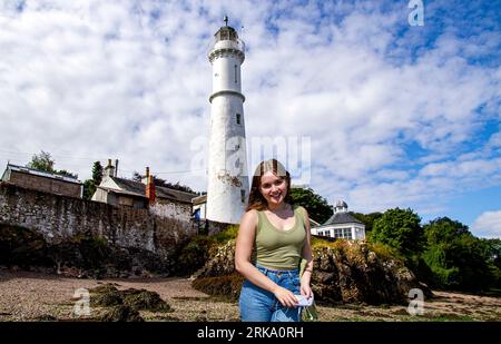 Image modifiée numériquement et modifiée dans Photoshop d'une femme Olivia (Lulu) Glen debout devant le phare de Tayport à Fife, en Écosse Banque D'Images