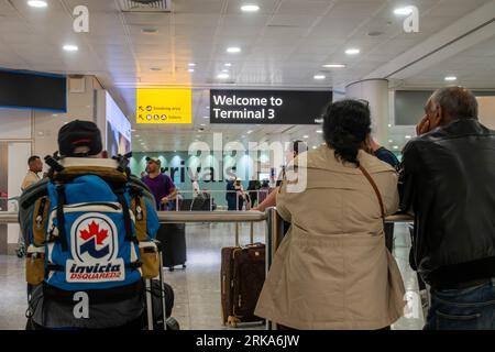 Les gens se tiennent debout et attendent leurs proches aux arrivées au terminal 3 de l'aéroport de Londres Heathrow à Londres, Royaume-Uni Banque D'Images