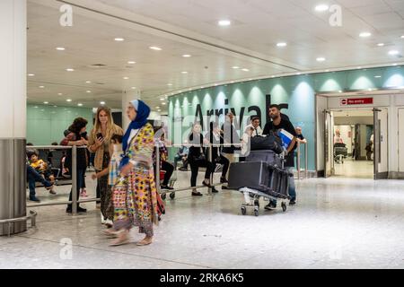 Passagers arrivant au terminal 3 de l'aéroport de Londres Heathrow, passant dans le hall des arrivées Banque D'Images