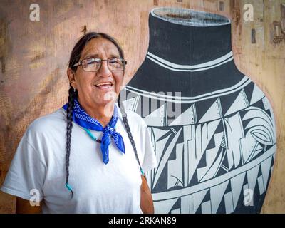 Un Amérindien pose devant des œuvres d'art représentant des poteries amérindiennes à Mesa Verde. Banque D'Images