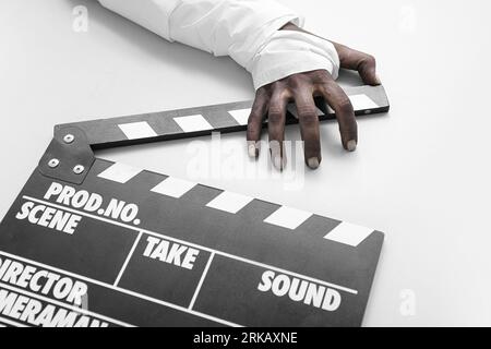 Main de zombie avec clapperboard sur fond blanc. Fête d'Halloween Banque D'Images