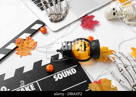 Clapperboard avec ordinateur portable et décor d'Halloween différent sur fond blanc Banque D'Images