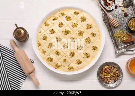 Faire de délicieux baklava. Pâte crue avec des ingrédients sur une table en bois blanc, mise à plat Banque D'Images