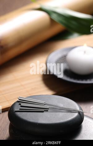 Pierres avec des aiguilles d'acupuncture sur une table en bois Banque D'Images