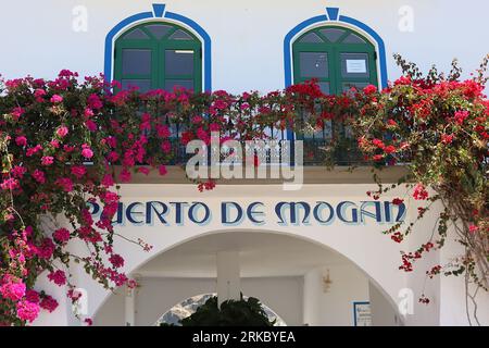 Extérieur d'une tour peinte traditionnellement à l'entrée du port de Playa de Mogan, Gran Canaria, décorée de Bougainvilliers rose vif, avril 2022. Banque D'Images