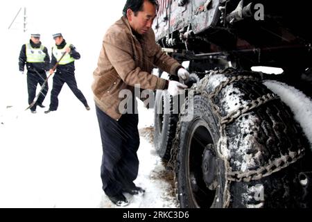 Bildnummer : 54658646 Datum : 18.11.2010 Copyright : imago/Xinhua (101119) -- ALTAY, 19 novembre 2010 (Xinhua) -- Un chauffeur de camion lie la chaîne de pneus pour empêcher le glissement sur une route provinciale dans le comté de Fuyun d'Altay, région autonome Uygur du Xinjiang du nord-ouest de la Chine, 18 novembre 2010. Une chute de neige a frappé la région jeudi, causant le blocage de plus de 150 véhicules sur la route provinciale couverte de glace. Les embouteillages ont été éliminés jeudi soir. (Xinhua/Ding Ning) (zgp) CHINA-XINJIANG-ALTAY-SNOW-TRAFFIC CONGESTION (CN) PUBLICATIONxNOTxINxCHN Gesellschaft Strasse Verkehr Wintereinbruch Schnee kbdig xub 2010 Banque D'Images