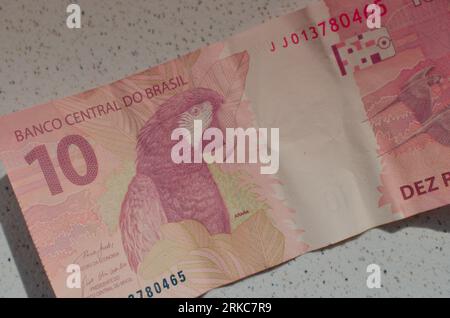 Détail du billet de banque de 10 reais do Brasil, une monnaie brésilienne mise en valeur par sa couleur rouge emblématique. Casa da Moeda do Brasil, représentant le B. Banque D'Images