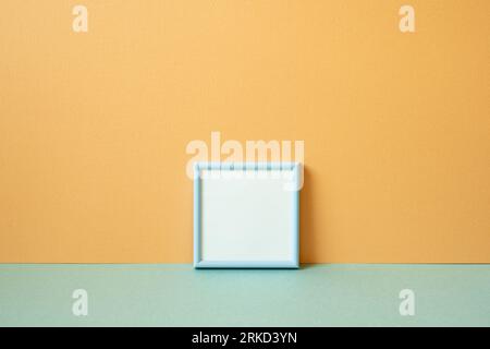 Cadre photo vide bleu sur la table vert menthe. fond de mur orange. espace de copie Banque D'Images