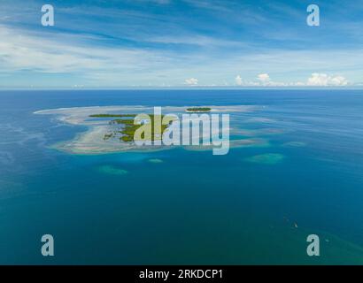 Vue des oiseaux de l'eau turquoise entourée dans la petite île tropicale et la forêt de mangroves. Récifs coralliens et vagues. Mindanao, Philippines. Banque D'Images