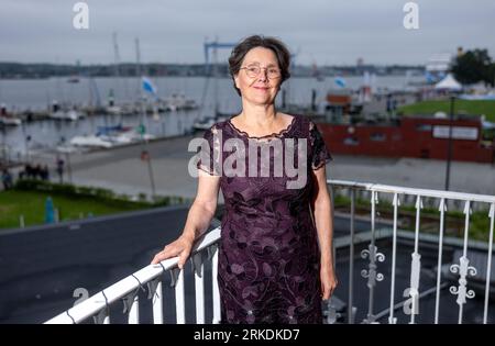 Kiel, Allemagne. 18 août 2023. Monika Heinold (Bündnis 90/Die Grünen), ministre des Finances du Schleswig-Holstein, se tient sur le balcon de son bureau dans le ministère devant le panorama du fjord de Kiel. Compte tenu de la situation budgétaire tendue, Heinold considère qu'une réduction des coûts de personnel est inévitable. (À dpa 'Heinold annonce un frein aux dépenses du personnel') crédit : Axel Heimken/dpa/Alamy Live News Banque D'Images