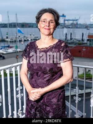 Kiel, Allemagne. 18 août 2023. Monika Heinold (Bündnis 90/Die Grünen), ministre des Finances du Schleswig-Holstein, se tient sur le balcon de son bureau dans le ministère devant le panorama du fjord de Kiel. Crédit : Axel Heimken/dpa/Alamy Live News Banque D'Images