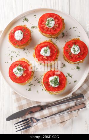 Courgettes dans une pâte à œufs servies avec sauce tzatziki et tomates fraîches en gros plan dans une assiette sur la table. Vue verticale de dessus Banque D'Images
