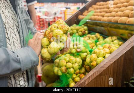 Femme choisissant des fruits frais emballés au supermarché. Client achetant de la nourriture dans des épiceries. Banque D'Images