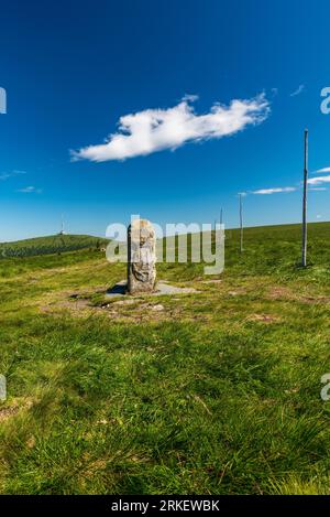 Vieille pierre de frontière sur la colline du trou de Vysoka avec la colline de Praded sur le fond dans les montagnes Jeseniky en république tchèque pendant la belle journée d'été Banque D'Images