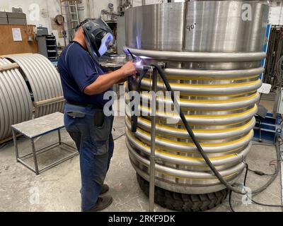 Un soudeur qualifié portant un équipement de protection, soudant une machine dans une usine Banque D'Images