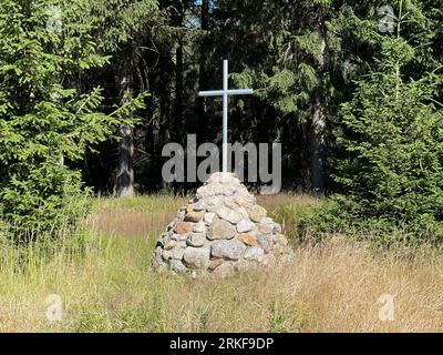 Une croix sur une petite colline rocheuse dans un champ herbeux Banque D'Images