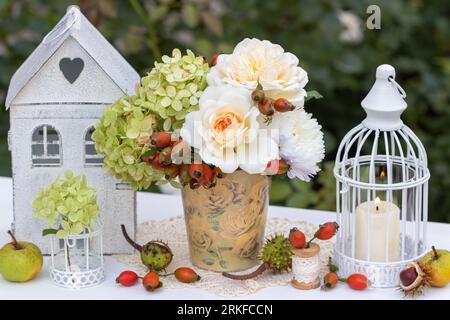 arrangement vintage avec bouquet de roses blanc crème, fleurs d'hortensia et hanches de rose, lanterne et bougie Banque D'Images