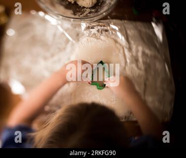 jeune fille à l'aide d'un emporte-pièce d'arbre de noël, photographié d'en haut Banque D'Images