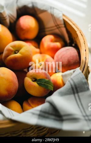 Gros plan du panier avec des pêches fraîches au soleil enveloppées dans une serviette Banque D'Images