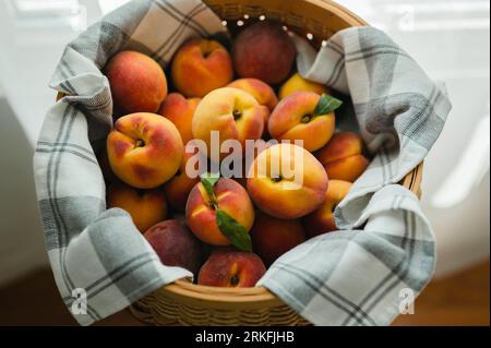 Vue de dessus des pêches mûres fraîches dans le panier dans un torchon de cuisine Banque D'Images