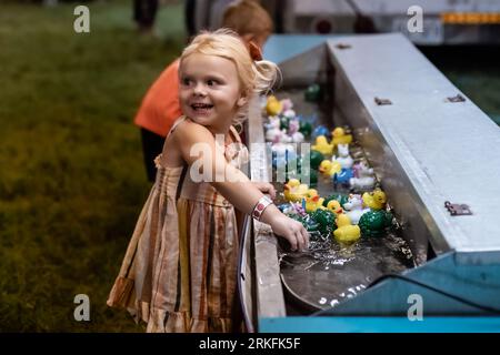 Enfants jouant au jeu de canard en caoutchouc au carnaval dans la soirée Banque D'Images