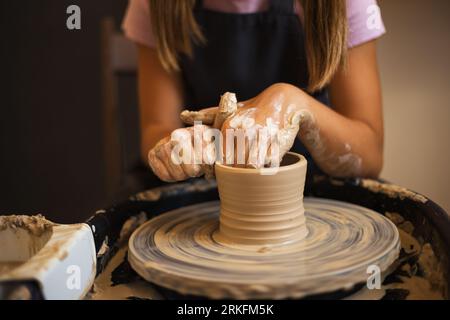 Gros plan des mains d'une adolescente modélisant de la poterie sur un potter wh Banque D'Images