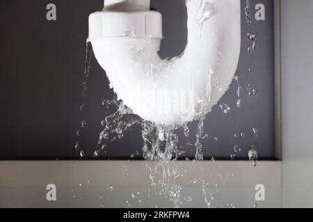 Les fuites d'eau à partir de la canalisation en acier inoxydable sur fond gris Banque D'Images